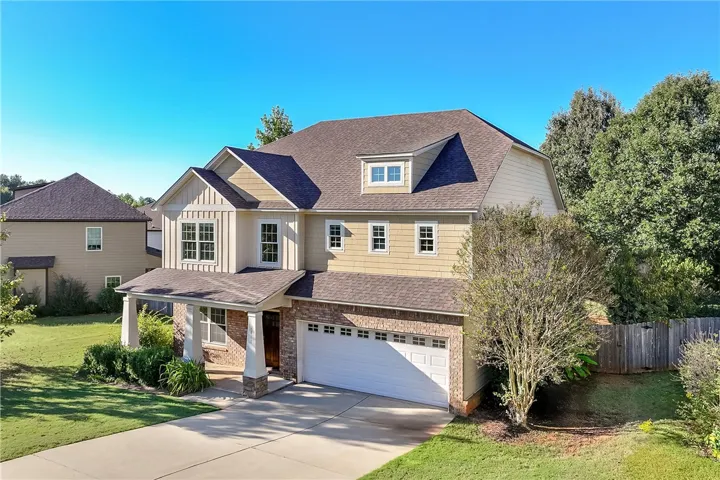 A spacious two-story brick and cement board home features a welcoming front porch and concrete driveway.