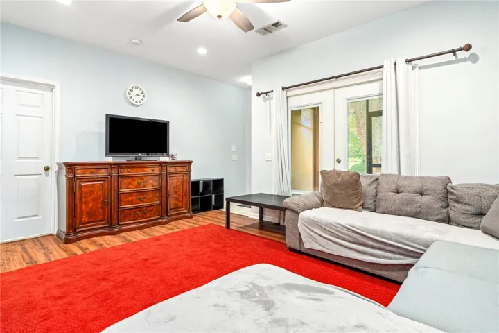 Warm wood flooring and glass-paned doors enrich this inviting living space.