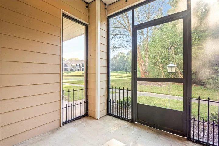 An inviting screened porch looks out over a tranquil neighborhood lake and grassy common area.