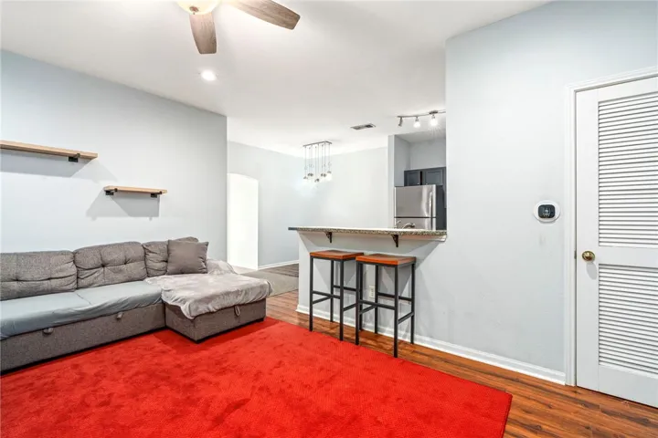 Warm wood flooring pairs seamlessly with a functional breakfast bar opening to the kitchen.