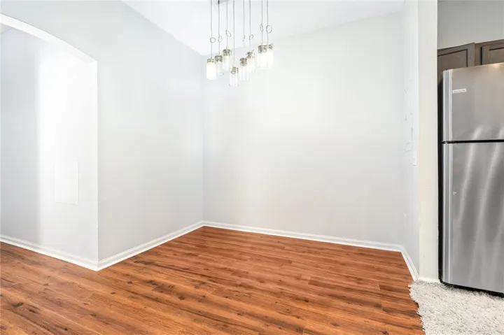 Warm wood flooring grounds this versatile space featuring an arched entryway and high ceilings.