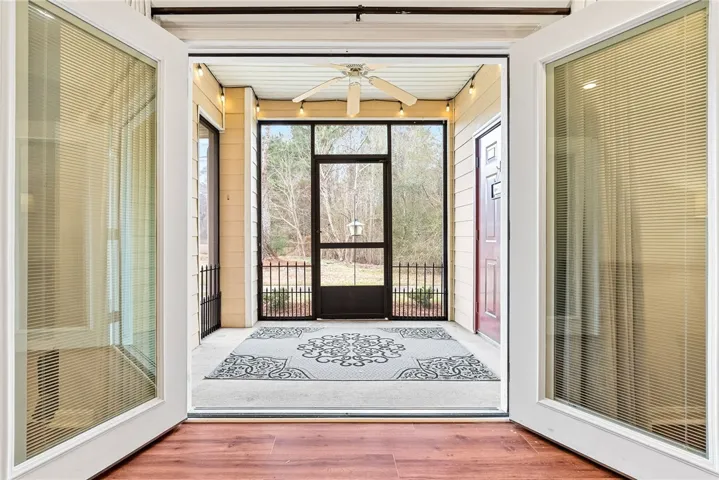 Double doors open to a screened porch overlooking peaceful wooded views.