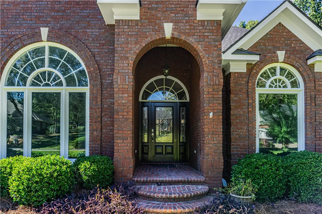 A grand arched brick entryway makes a striking architectural statement flanked by large Palladian windows.