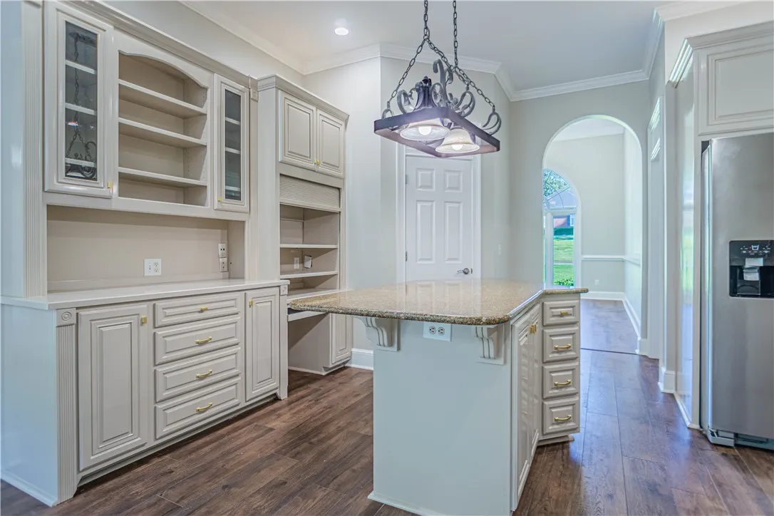 Gleaming hardwood floors and a central prep island anchor this well-appointed kitchen space.
