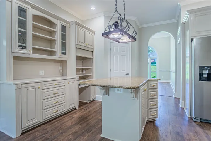 Gleaming hardwood floors and a central prep island anchor this well-appointed kitchen space.