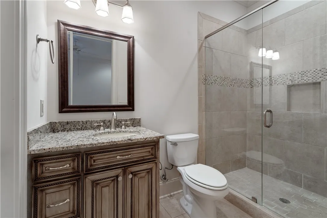 Fine granite countertops and a tiled walk-in shower elevate this elegant bathroom space.