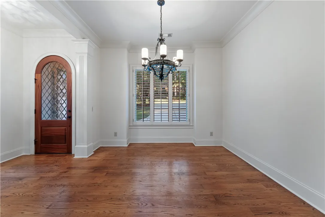 Hardwood floors and an arched wood entryway door enhance this formal dining area.