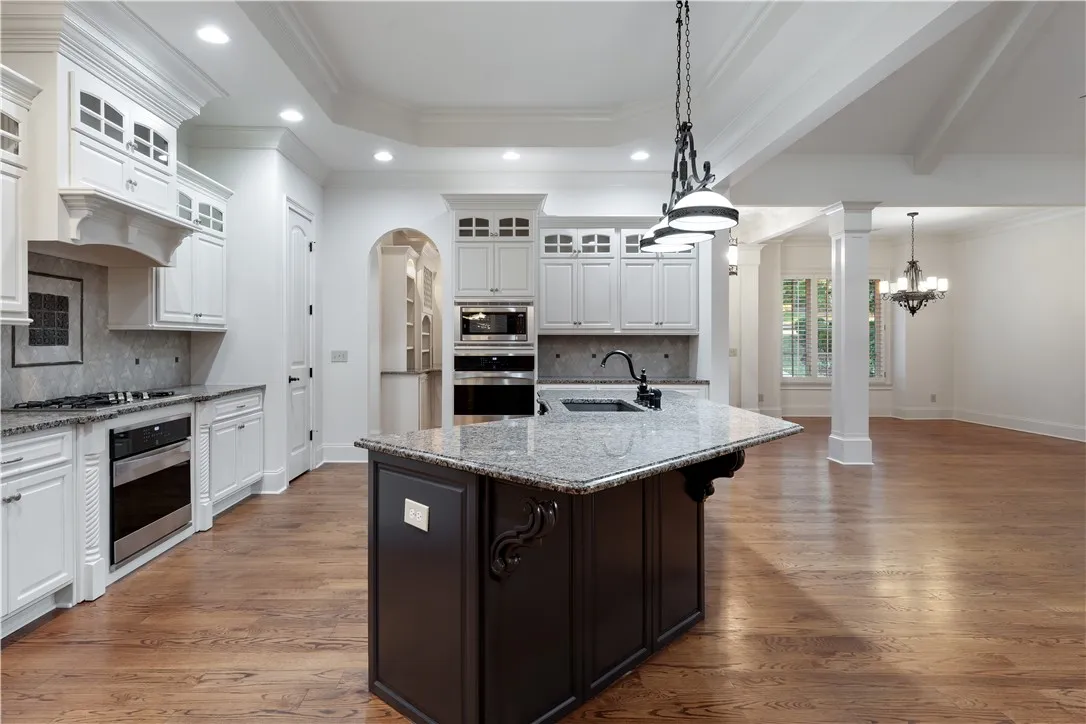 Gleaming hardwood floors and a massive center island anchor this open-concept culinary space.
