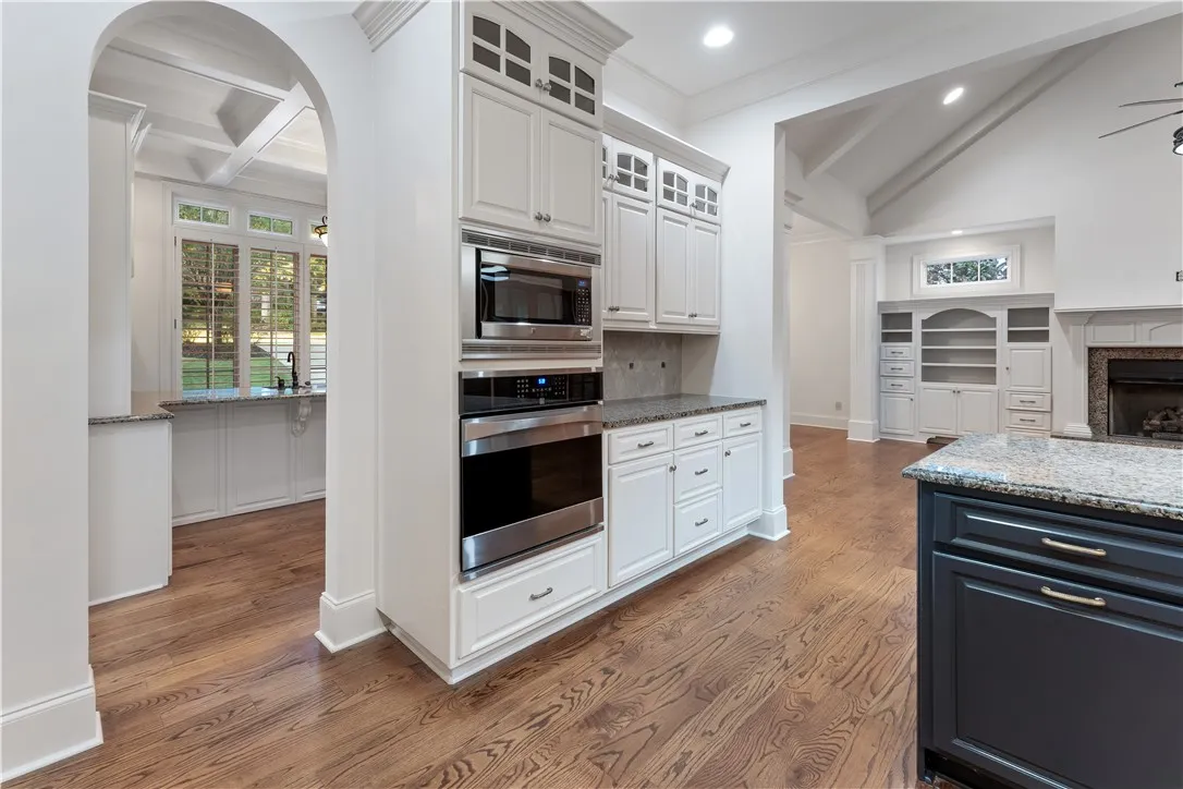 Gleaming hardwood floors run through a kitchen complete with custom cabinetry and granite countertops.