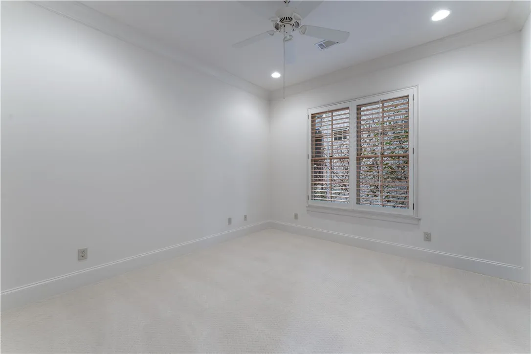 Crisp trim work and soft carpeting frame a bright window in this versatile bedroom.