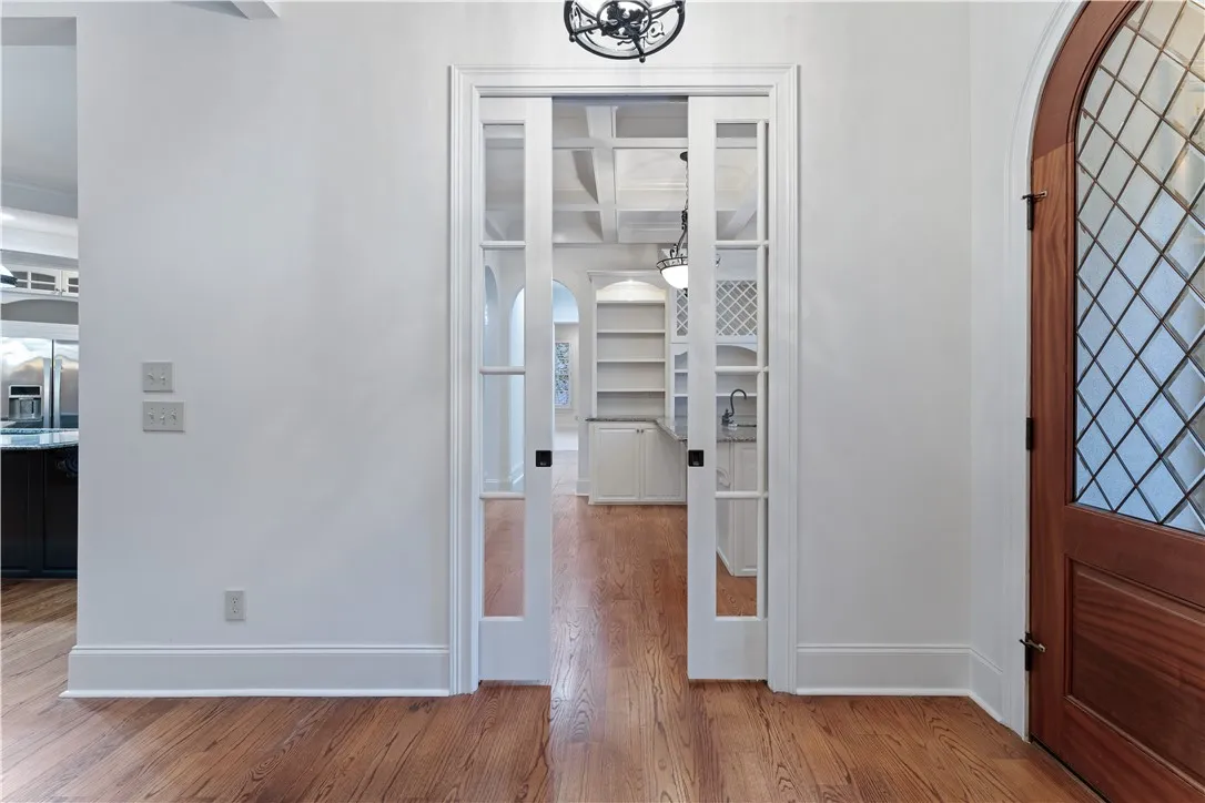 Elegant glass pocket doors open into a bright room with warm hardwood flooring.