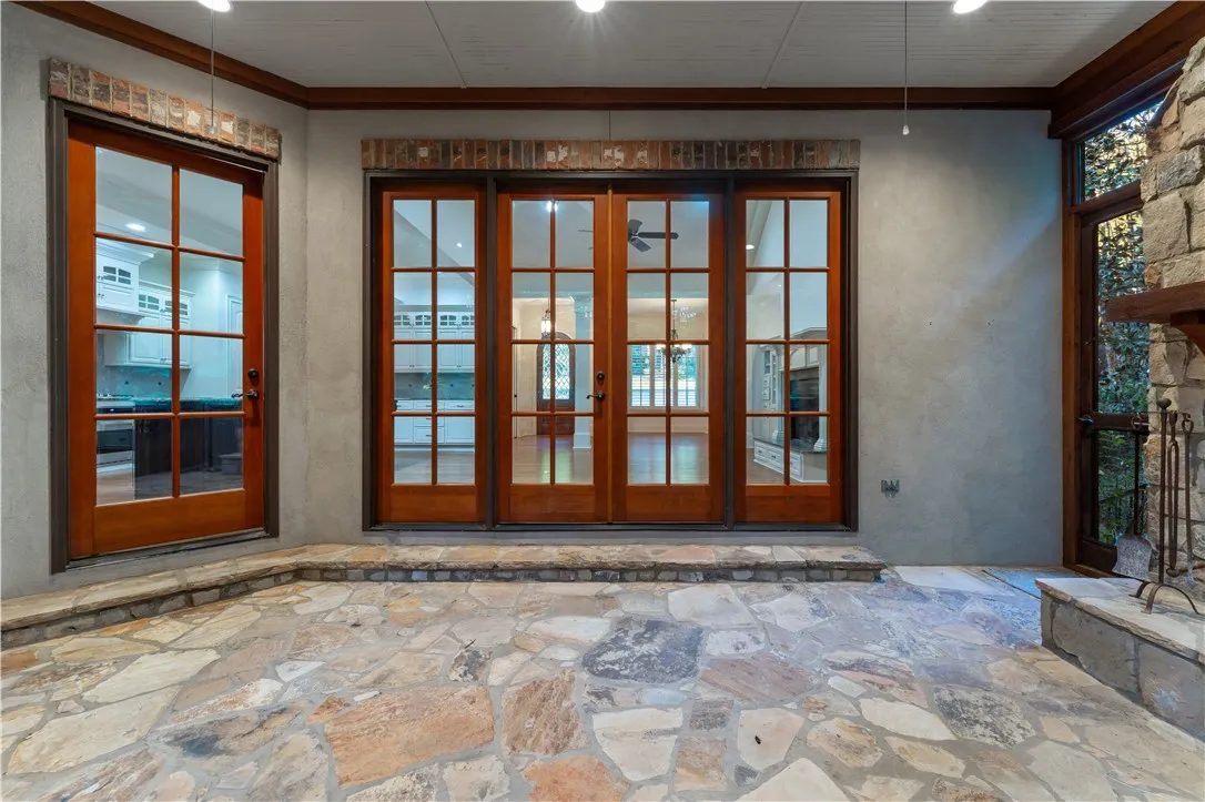 Stone flooring and brick lintels frame the wood-trimmed French doors leading inside.
