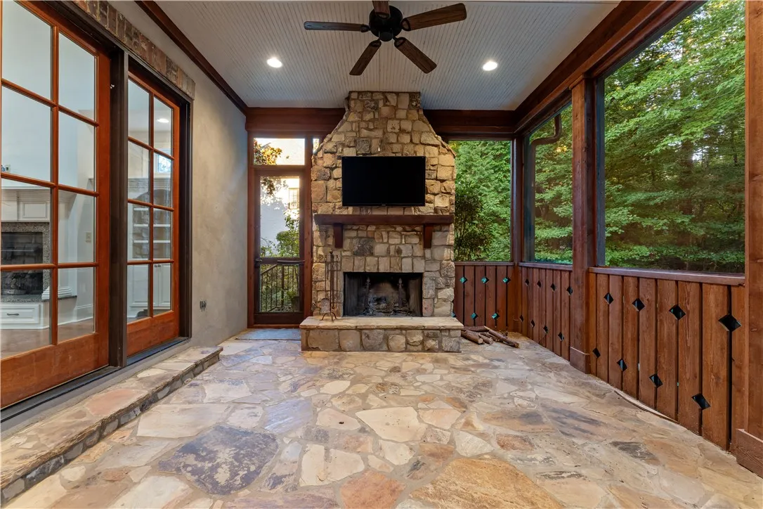 Natural flagstone flooring and a soaring stone fireplace ground this inviting screened porch.