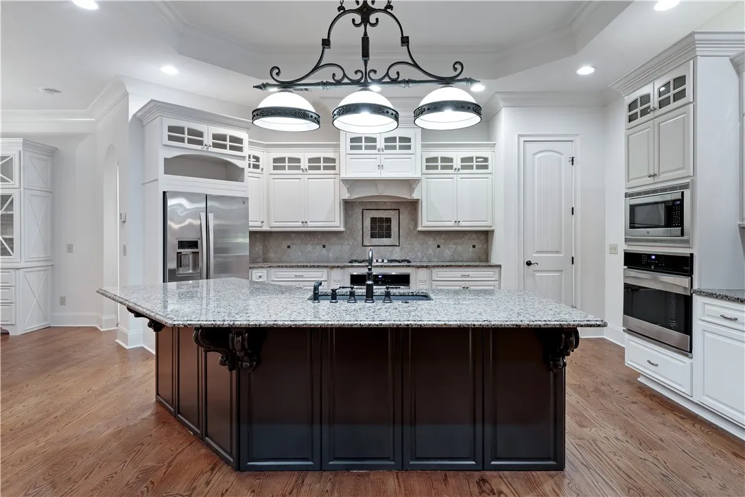 Granite countertops and warm wood floors anchor this finely detailed gourmet kitchen space.