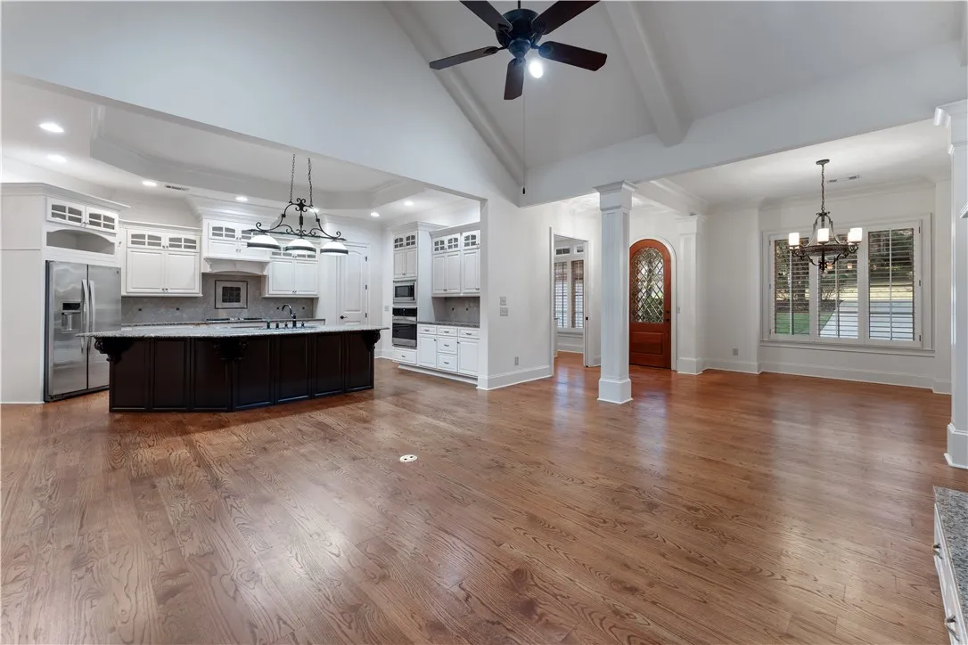 Rich hardwood floors sweep across an open-concept layout beneath soaring vaulted ceilings.