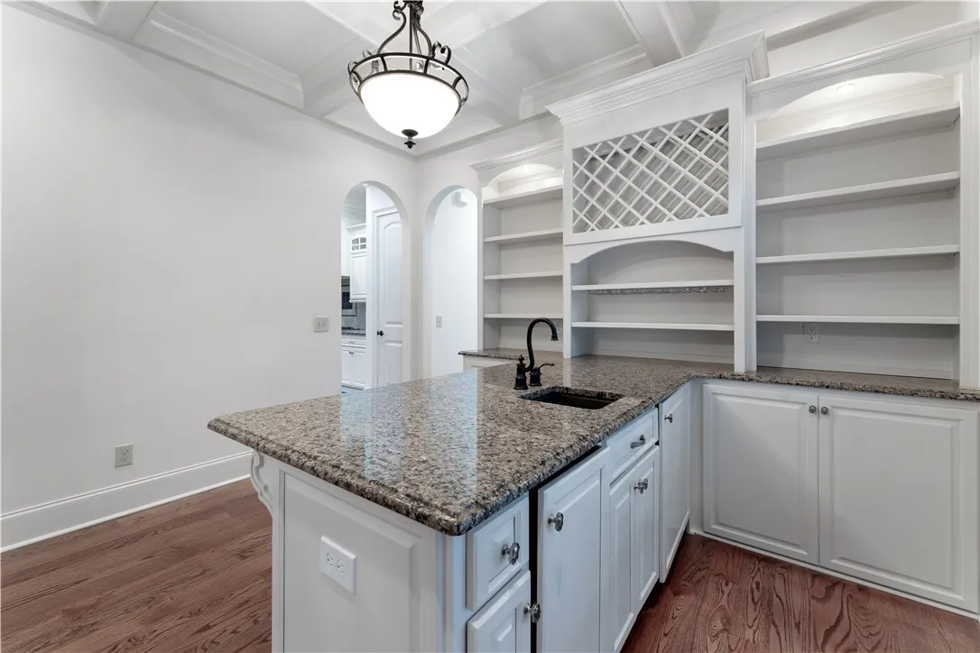Gleaming stone countertops and customized built-ins define this functional wet bar area.