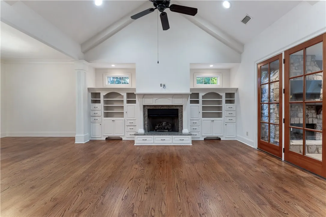 Rich hardwood flooring complements a fireplace flanked by custom built-ins under a soaring ceiling.