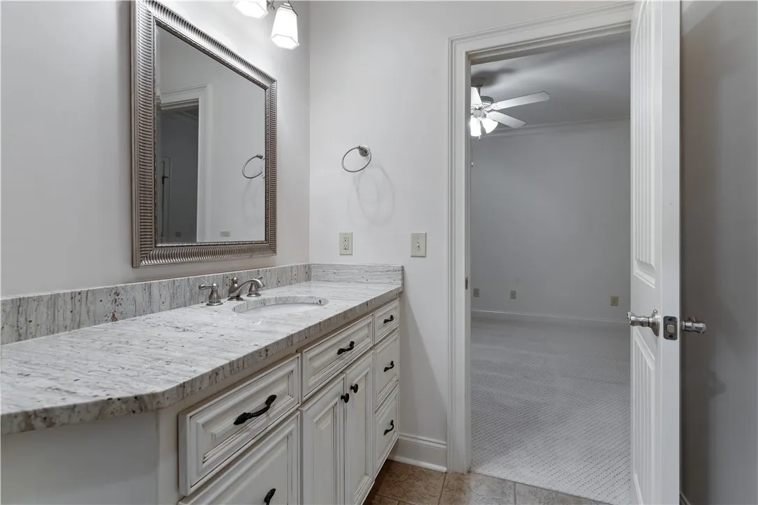 Upstairs. A classic vanity featuring stone counters and raised-panel cabinetry stands outside an adjoining carpeted room.