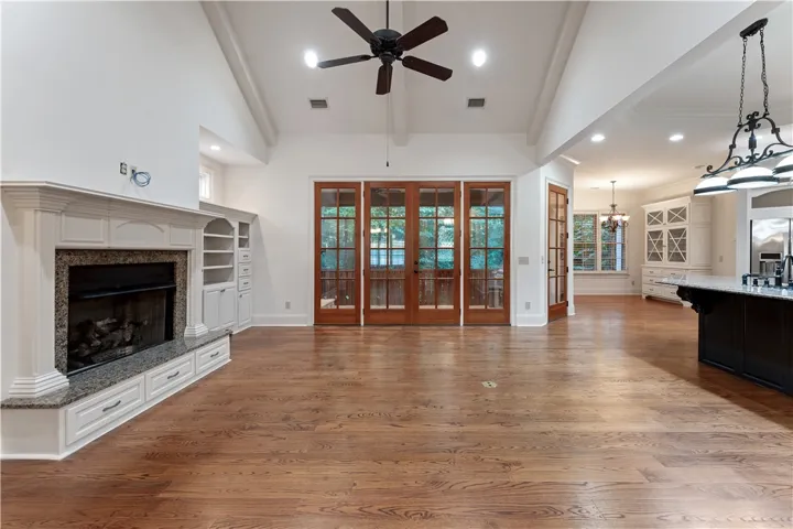 Rich hardwood flooring complements a classic fireplace and soaring vaulted ceilings in this open layout.