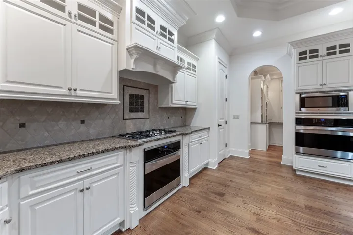 Gleaming hardwood floors complement granite countertops and custom cabinetry in this spacious kitchen.