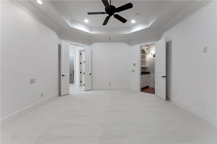 Plush carpeting anchors this spacious bedroom featuring an elegant tray ceiling and classic crown molding.