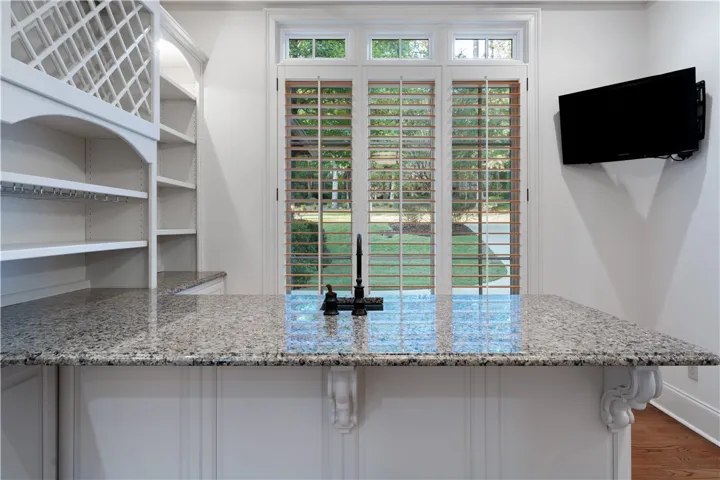 Polished stone counters and custom built-in shelving anchor this elegant wet bar area.
