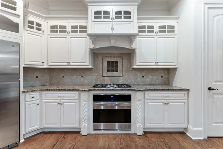 Rich hardwood flooring complements custom cabinetry and granite countertops in this upscale kitchen.
