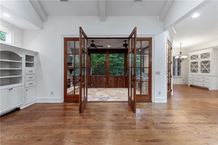 French doors connect a living space with rich hardwood flooring to a covered porch.