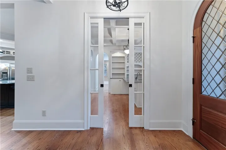 Elegant glass pocket doors open into a bright room with warm hardwood flooring.