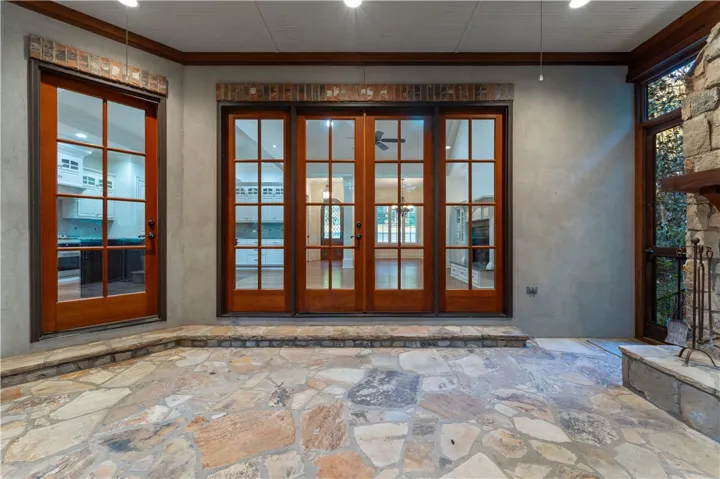 Stone flooring and brick lintels frame the wood-trimmed French doors leading inside.