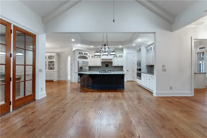Hardwood floors and vaulted ceilings frame the transition into a spacious modern kitchen.