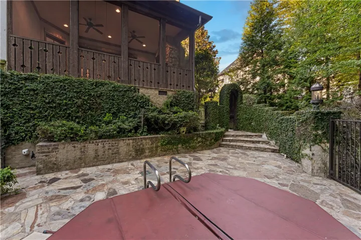 An inviting stone patio offers a private spa surrounded by lush ivy-covered walls.