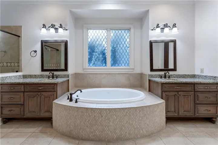 An integrated soaking tub centers this symmetric layout between two matching wood vanities.
