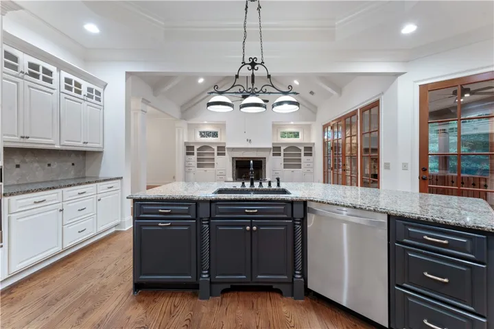 Rich hardwood floors complement the expansive granite island in this beautifully designed kitchen.
