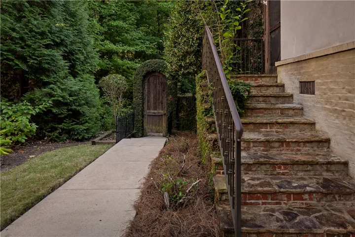Stone and brick stairs lead up past an ivy-covered garden wall to a private entrance.