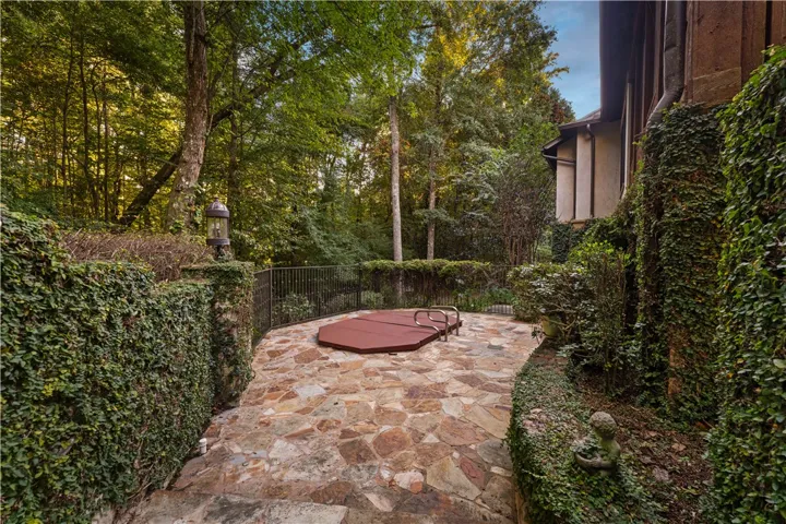 Mature trees frame a private flagstone terrace featuring an in-ground spa.
