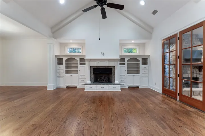 Rich hardwood flooring complements a fireplace flanked by custom built-ins under a soaring ceiling.