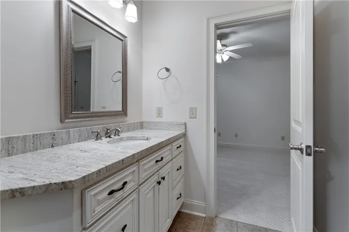 Upstairs. A classic vanity featuring stone counters and raised-panel cabinetry stands outside an adjoining carpeted room.