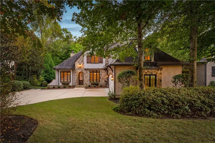 Mature trees frame the stone and stucco facade of this elegant residence.