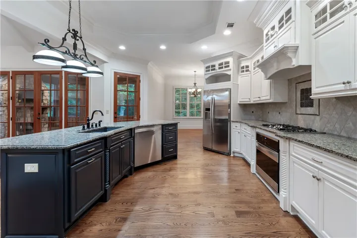 Rich hardwood flooring complements custom cabinetry and stone countertops in this open culinary space.