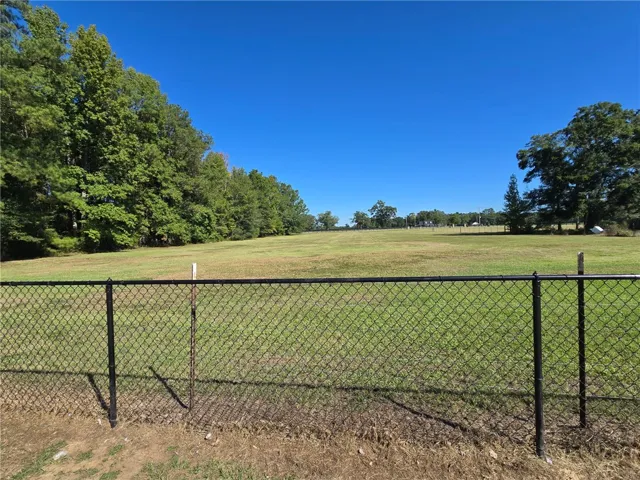 Mature trees frame a level grassy clearing bordering the property line.