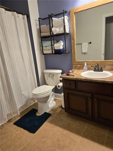 A classic bathroom layout includes a warm-toned vanity and matching tile flooring.