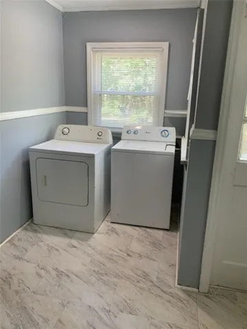 A functional laundry area features classic chair rail molding and durable vinyl flooring.