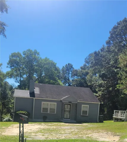 Mature trees frame a classic single-story home with a gabled roofline and cozy front porch.