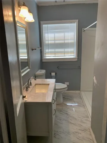 Marble-patterned flooring and a stone vanity top highlight this updated bath space.