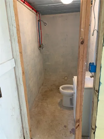 A functional basement bathroom layout featuring concrete floors, a simple vanity, and a shower area.