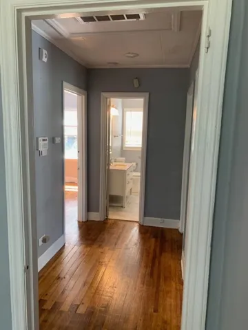 Gleaming hardwood floors connect the central hallway to adjacent rooms and a bathroom.