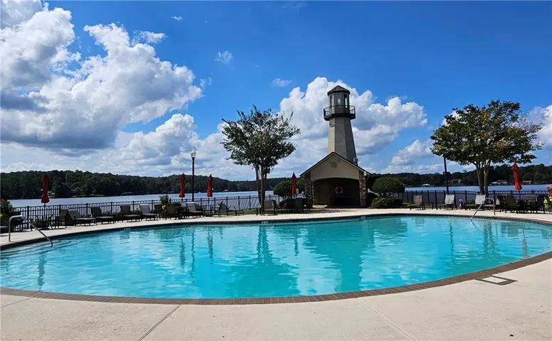 A sparkling lakeside swimming pool offers scenic water views next to an iconic lighthouse structure.