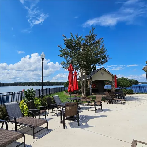 A spacious concrete patio overlooks the water under a clear blue sky.