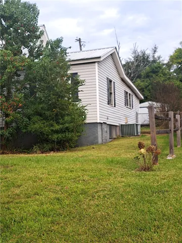 A grassy side yard borders this classic home with light siding and dark shutters.